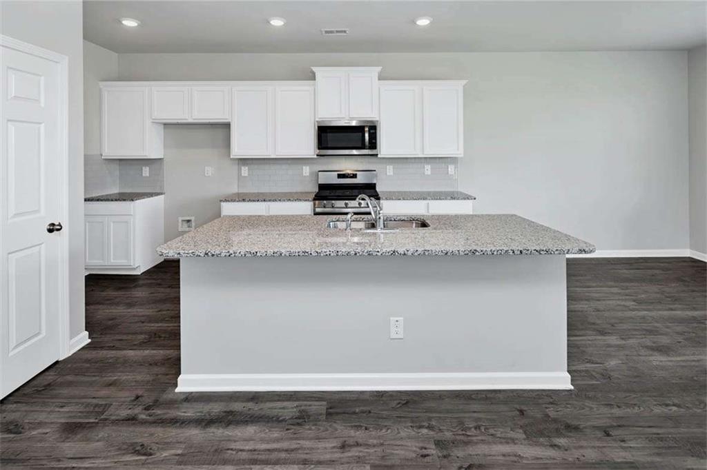 197 Lauritsen Way Newnan, GA 30265 - Photo 12 of 33 a kitchen with kitchen island granite countertop a sink stove and microwave