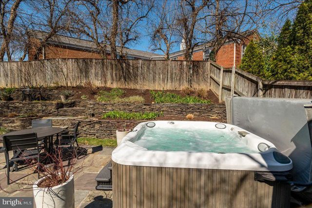 a kitchen with kitchen island granite countertop a sink a stove a refrigerator and white cabinets with wooden floor