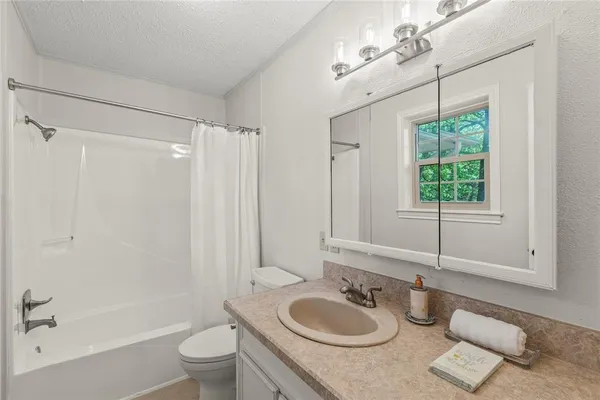 a bathroom with a granite countertop sink toilet a mirror a bathtub and shower