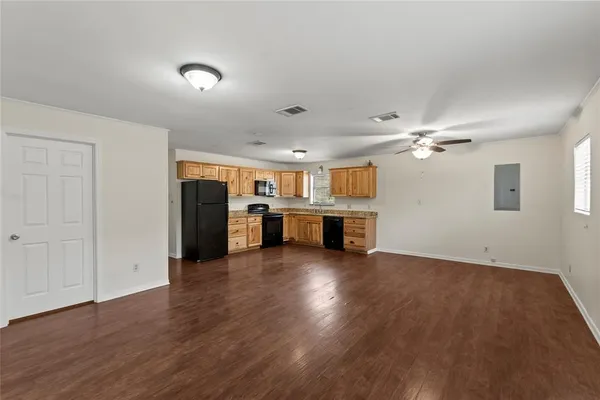 a view of a kitchen with a sink a refrigerator a kitchen island wooden floor and staircase