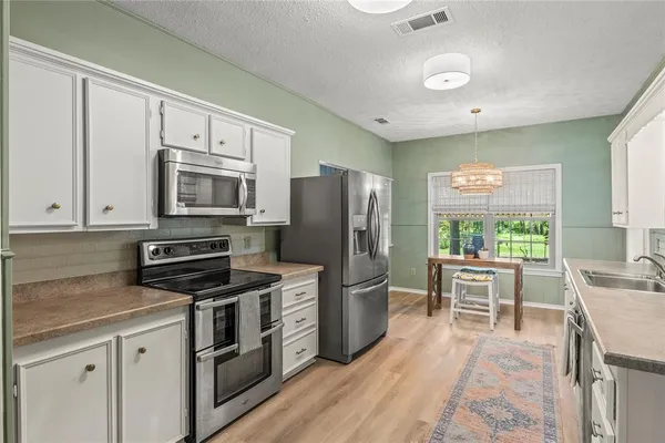 a kitchen with stainless steel appliances a stove refrigerator sink and microwave