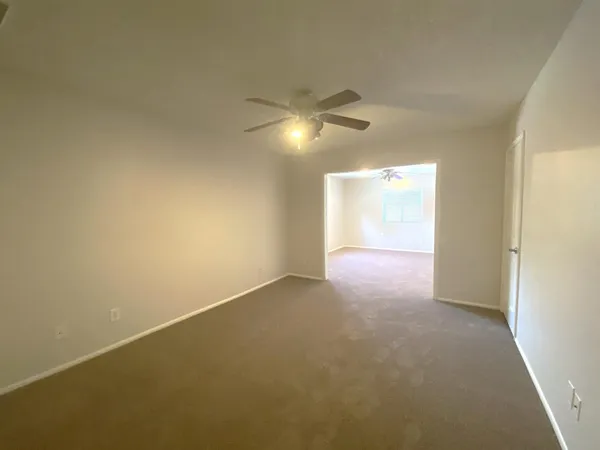 a view of an empty room with a chandelier fan