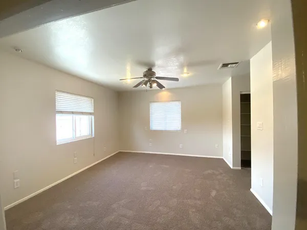 an empty room with windows and fan