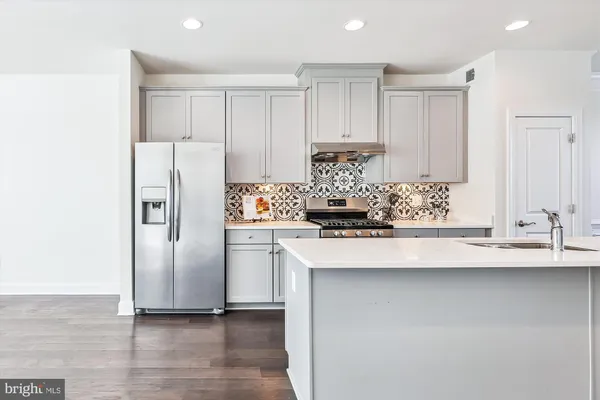 a kitchen with stainless steel appliances a refrigerator a stove and white cabinets