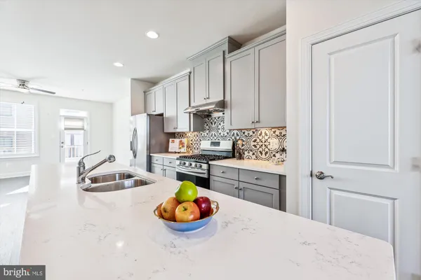 a kitchen with stainless steel appliances a sink a stove a refrigerator and white cabinets
