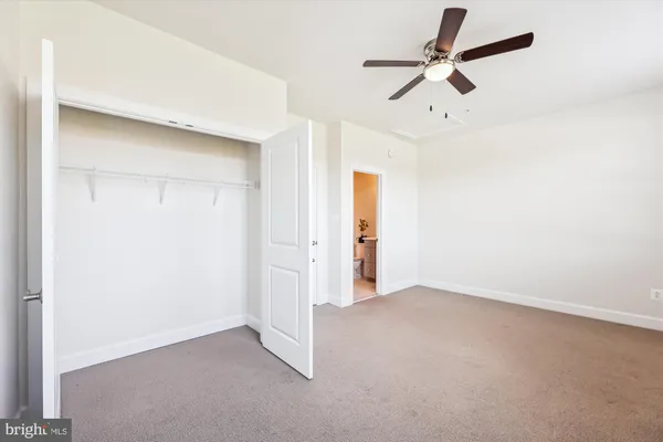 an empty room with closet and a ceiling fan