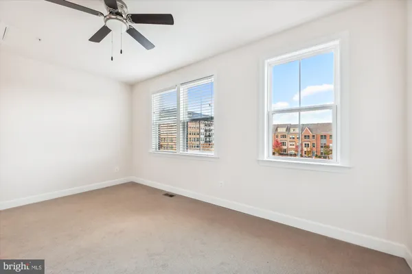 an empty room with windows and fan
