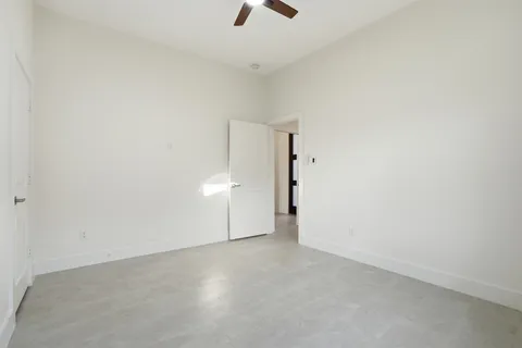 an empty room with chandelier fan and windows