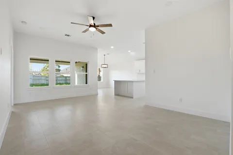 an empty room with windows and ceiling fan