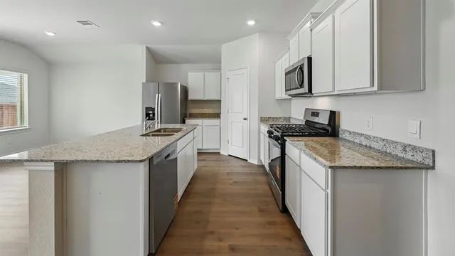 a kitchen with stainless steel appliances granite countertop white cabinets and a stove top oven