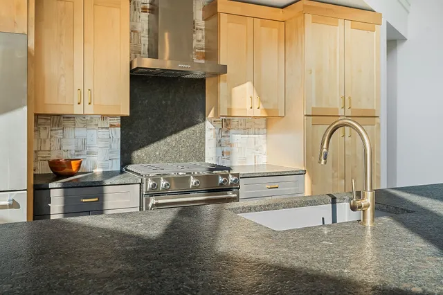 a kitchen with stainless steel appliances granite countertop a sink a stove and a refrigerator