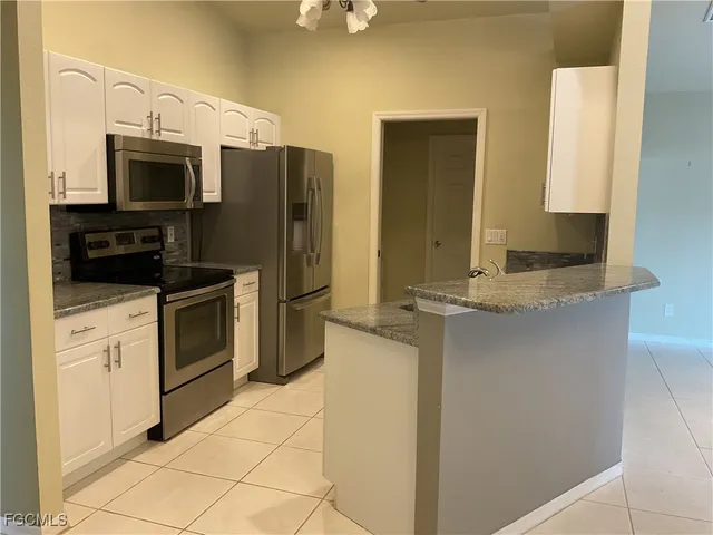 a kitchen with stainless steel appliances granite countertop a refrigerator and a stove top oven
