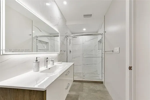 a bathroom with a sink shower and a mirror