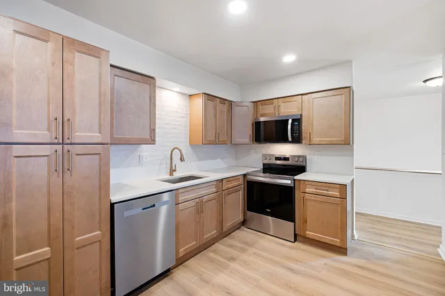 a kitchen with stainless steel appliances granite countertop a stove top oven a sink and dishwasher with wooden floor