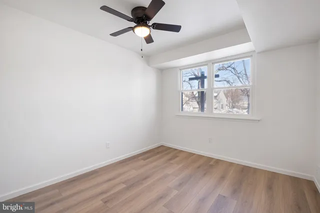 an empty room with wooden floor and ceiling fan