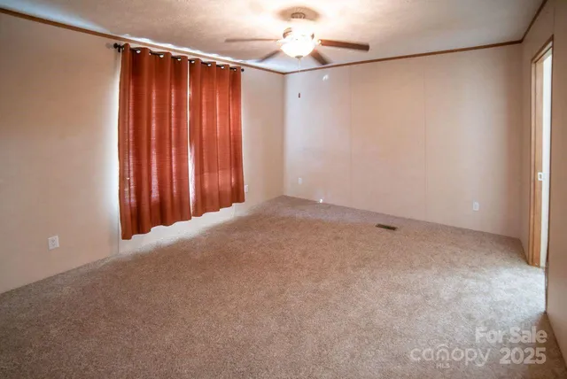 en empty room with a chandelier fan and windows