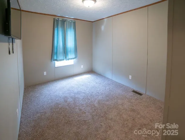 a view of an empty room with window and closet area