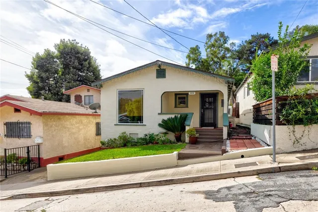 a front view of a house with a yard and potted plants