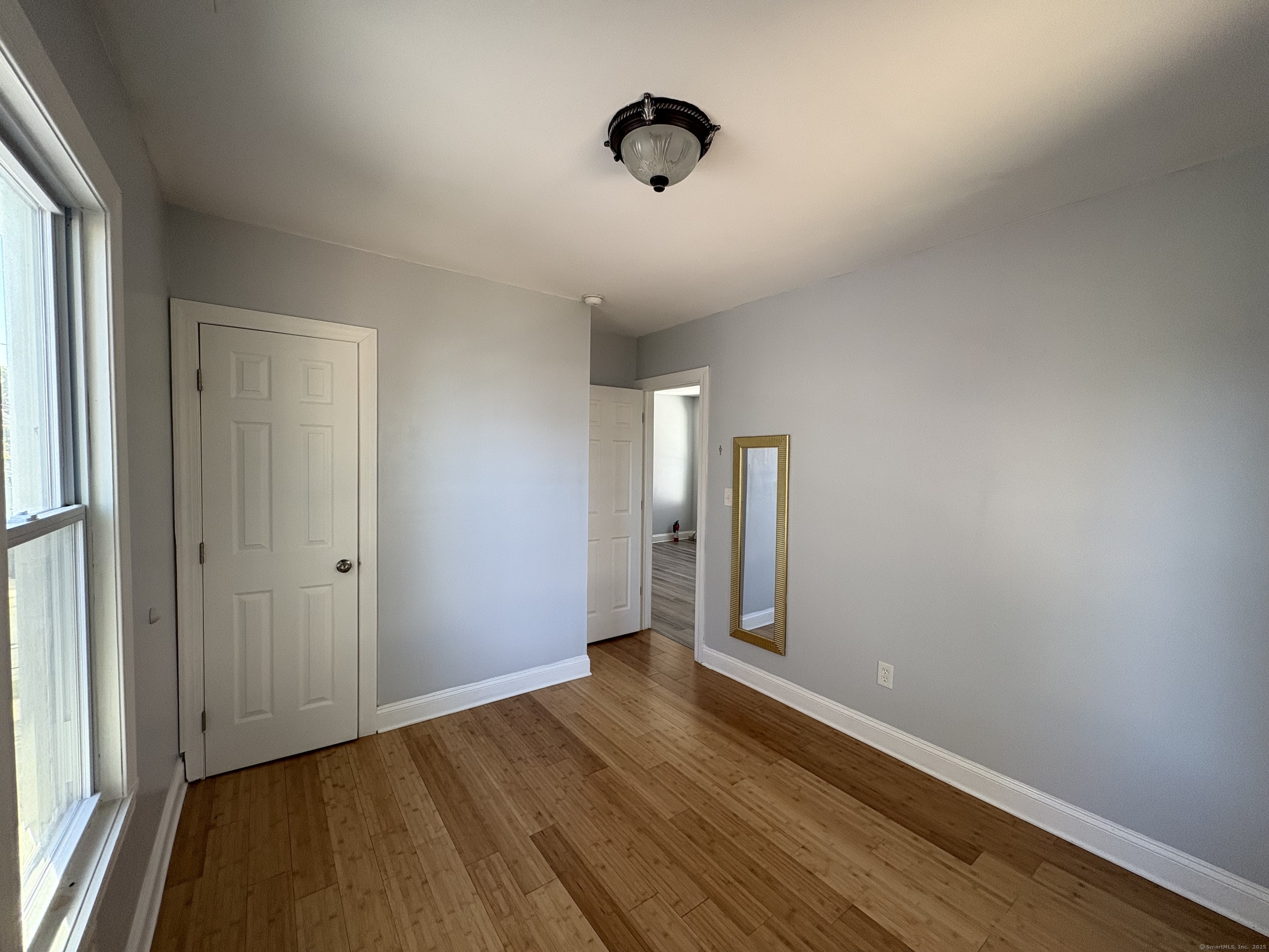 679 Shelton Street, Unit 2 Bridgeport, CT 06608 - Photo 6 of 25 a view of an empty room with wooden floor and a window