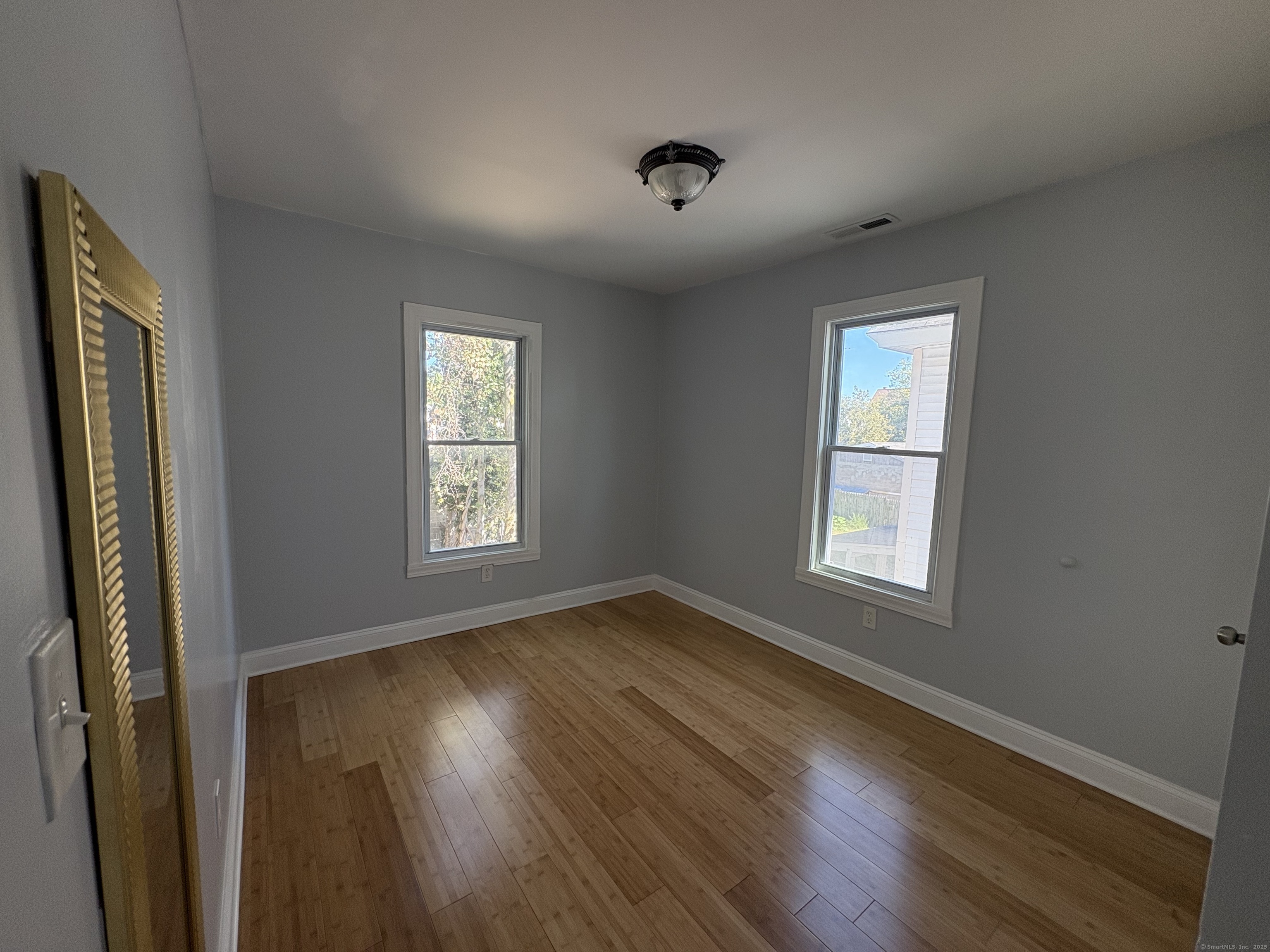 679 Shelton Street, Unit 2 Bridgeport, CT 06608 - Photo 7 of 25 a view of an empty room with wooden floor and a window