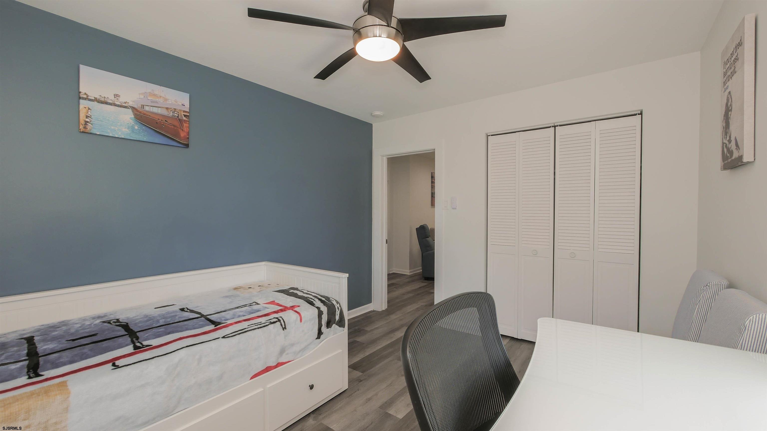 11 South Washington Avenue, Unit 2 Margate City, NJ 08402 - Photo 19 of 35 a bedroom with a bed and a chandelier