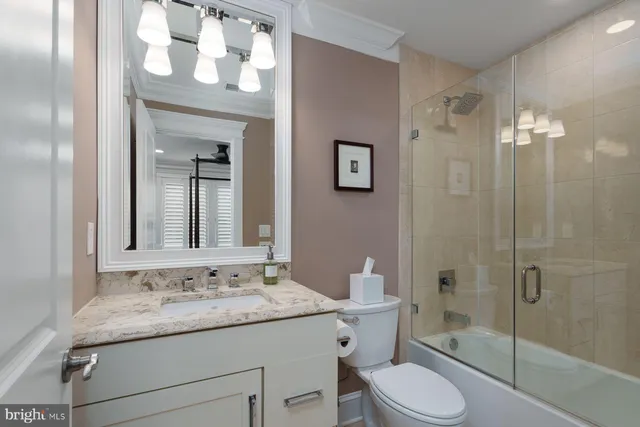 a bathroom with a granite countertop sink toilet a mirror a vanity and shower