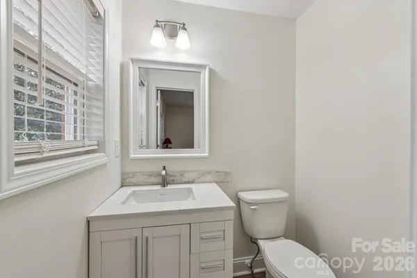 a bathroom with a granite countertop toilet a sink and a window