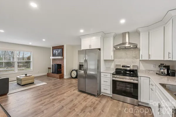 a kitchen with stainless steel appliances a stove a sink a refrigerator white cabinets and wooden floor