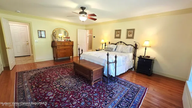 a spacious bedroom with a bed a dresser and wooden floor