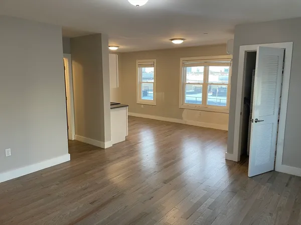 an empty room with wooden floor and windows