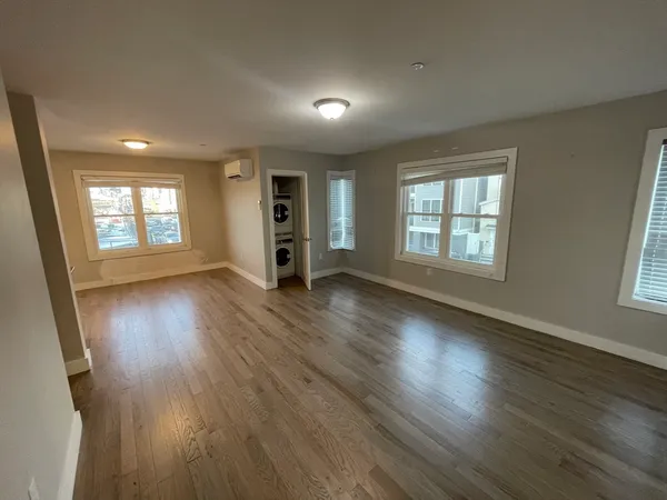 an empty room with wooden floor and windows