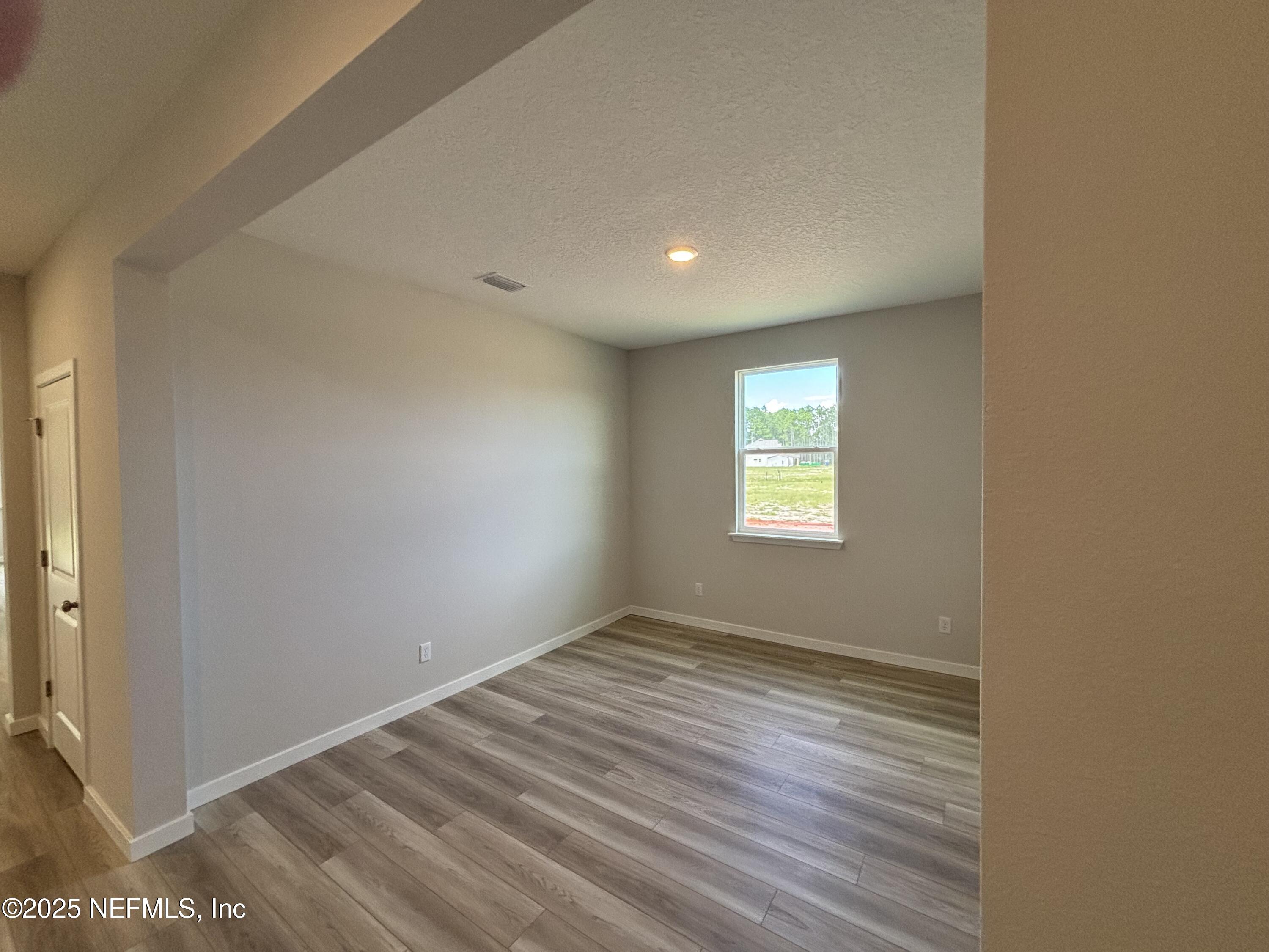 71 Pegasus Road Flagler Beach, FL 32136 - Photo 7 of 25 an empty room with wooden floor and windows