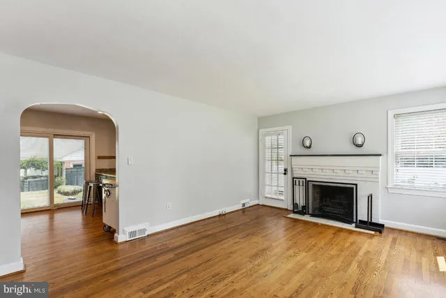 an empty room with wooden floor fireplace and windows