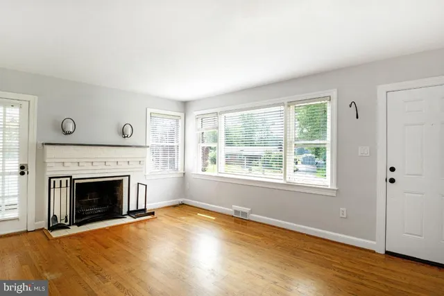 an empty room with wooden floor fireplace and windows