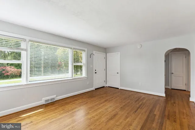 an empty room with wooden floor and windows