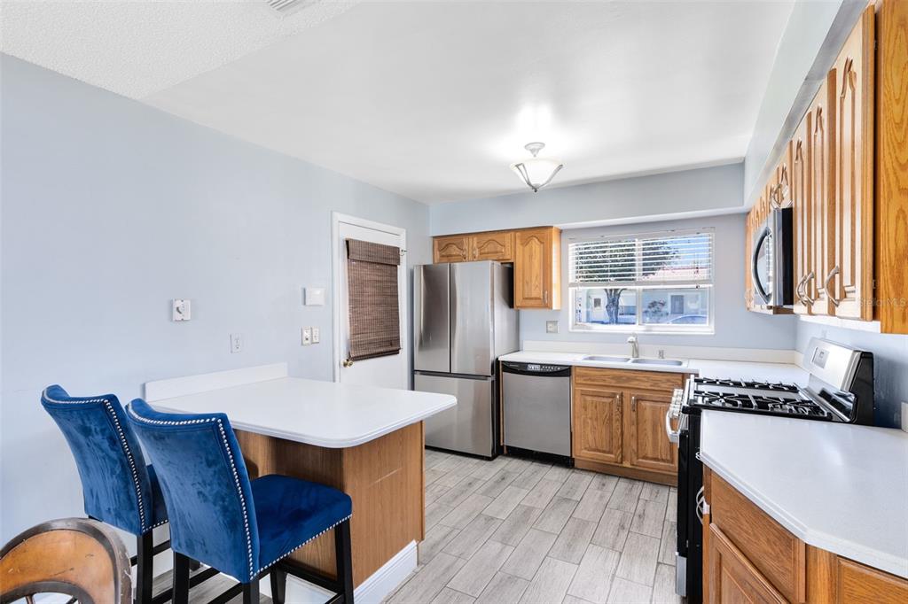 5331 Maize Street Orlando, FL 32821 - Photo 14 of 35 a kitchen with stainless steel appliances granite countertop a stove a sink dishwasher a couches and chairs with wooden floor