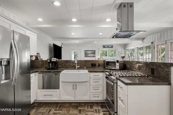 a kitchen with stainless steel appliances kitchen island granite countertop a sink a stove a refrigerator cabinets and chairs