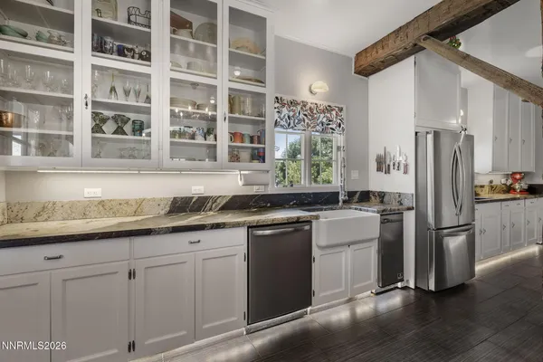 a kitchen with stainless steel appliances granite countertop a refrigerator a sink a stove and white cabinets with wooden floor