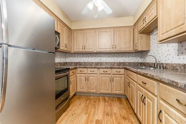 a kitchen with granite countertop a sink stainless steel appliances and cabinets