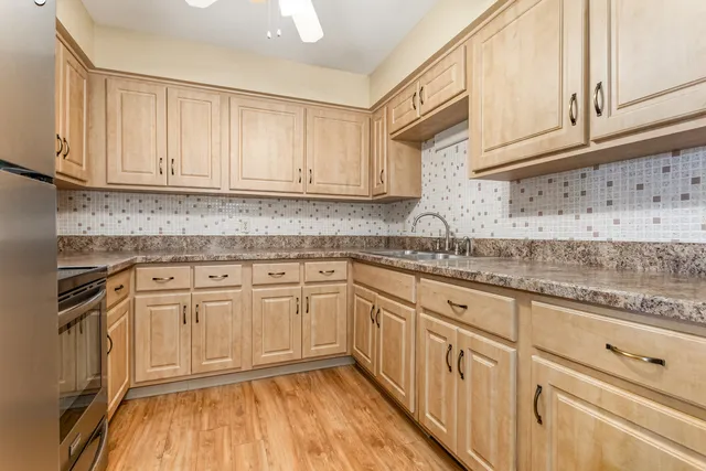 a kitchen with granite countertop cabinets stainless steel appliances wooden floor and a sink