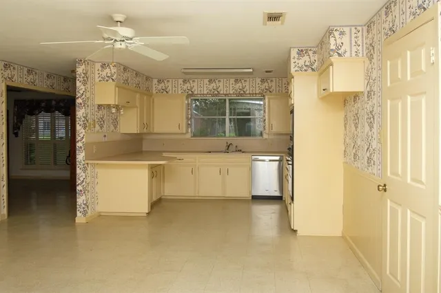 a utility room with stainless steel appliances a stove a sink and white cabinets