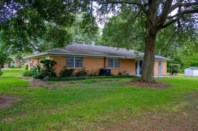 a front view of house with a garden and trees