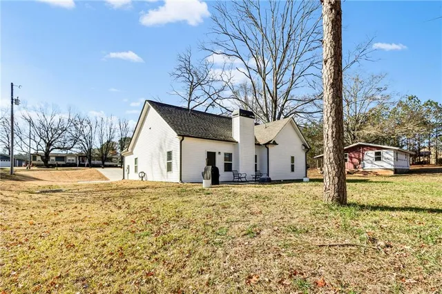 a view of a white house next to a yard with a large tree
