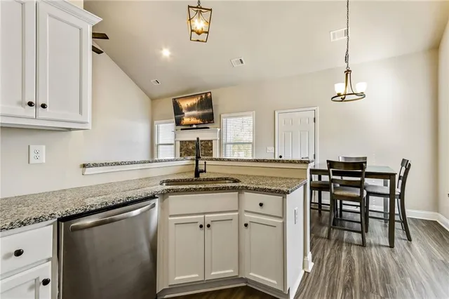 a kitchen with stainless steel appliances granite countertop a sink a stove and white cabinets