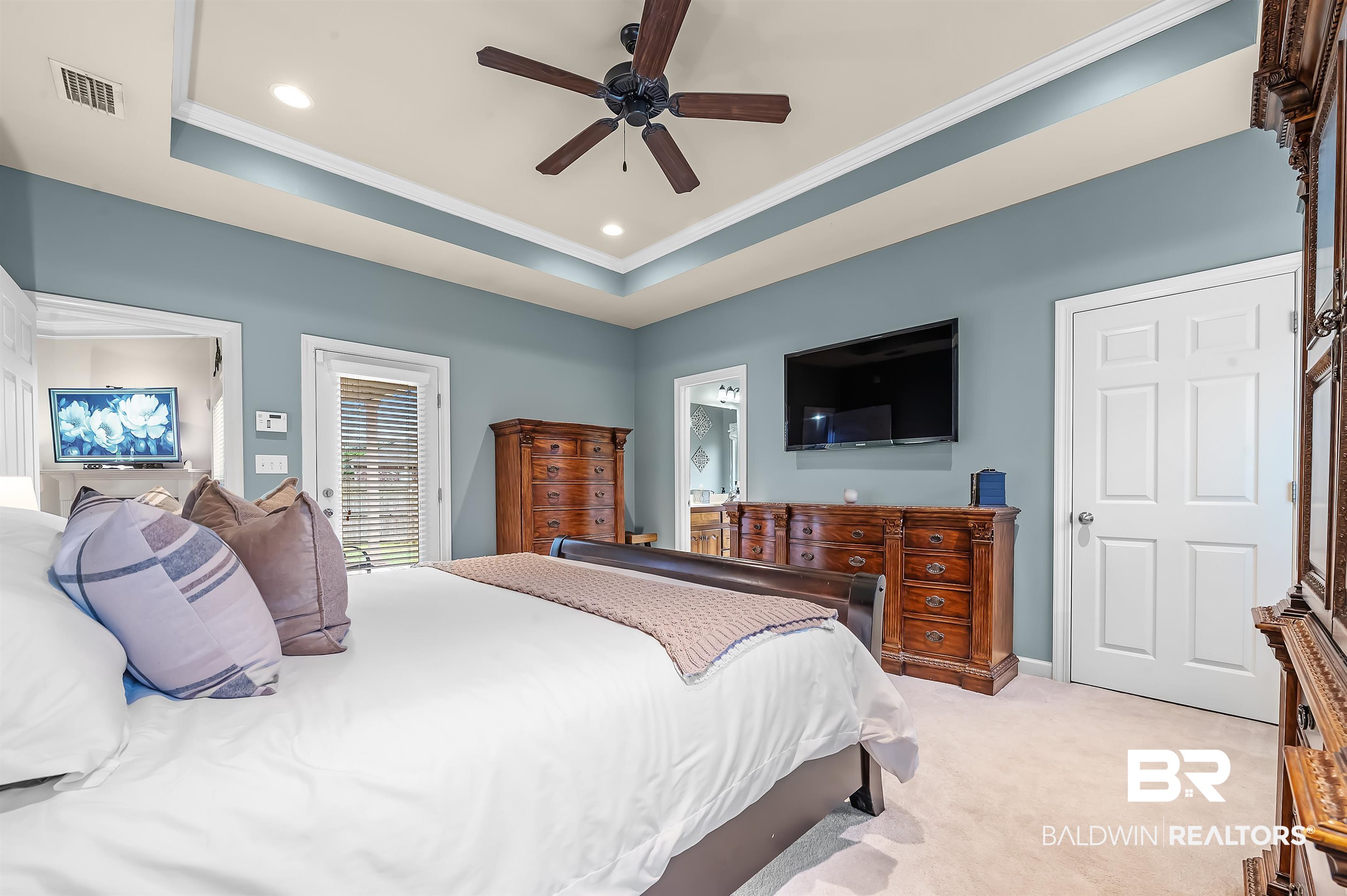 9376 Sable Court Daphne, AL 36526 - Photo 23 of 46 Carpeted bedroom with a tray ceiling, ceiling fan, connected bathroom, and ornamental molding