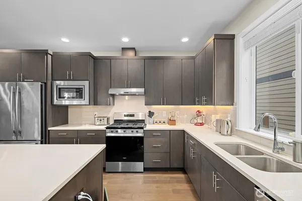 a kitchen with kitchen island stainless steel appliances a sink a stove a refrigerator cabinets and a center island