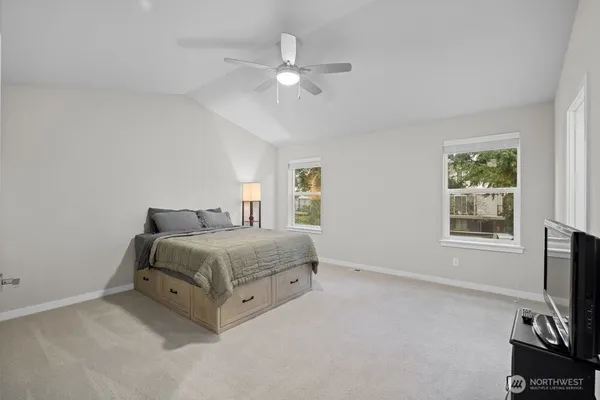 a spacious bedroom with a bed flat screen tv and a window