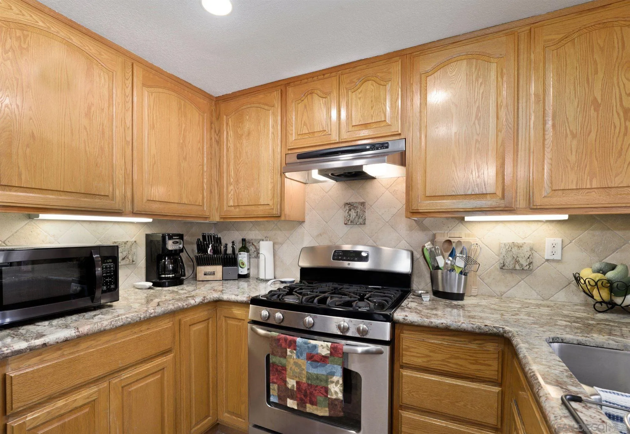 910 Redbud Road Chula Vista, CA 91910 - Photo 8 of 33 a kitchen with granite countertop wooden cabinets and a stove top oven