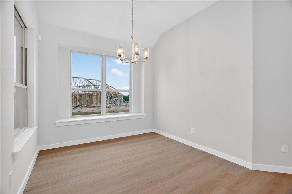 321 Skeen Peak Springtown, TX 76082 - Photo 18 of 37 Open room featuring wood-finish flooring, white baseboards, and a contemporary chandelier