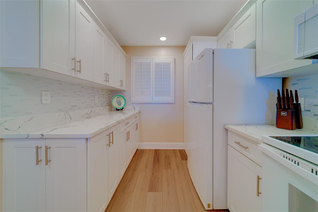 18304 Gulf Boulevard, Unit 102 Redington Shores, FL 33708 - Photo 11 of 55 a kitchen with white cabinets and white appliances